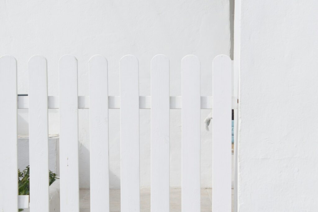 White wooden picket fence in front of a White House. White on white.